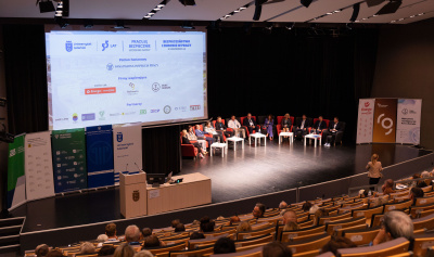 Konferencja BHP - widok sceny z panelistami, w tle plansza z logotypami partnerów i sponsorów