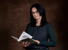 Julia Możdżeń na ciemno-brązowym tle, trzymająca książkę