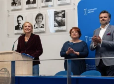 Katarzyna Smolarz, Mirosława Malinowska i Mariusz Czepczyński stoją za stołem prezydialnym w auli, pani dziekan przy mównicy