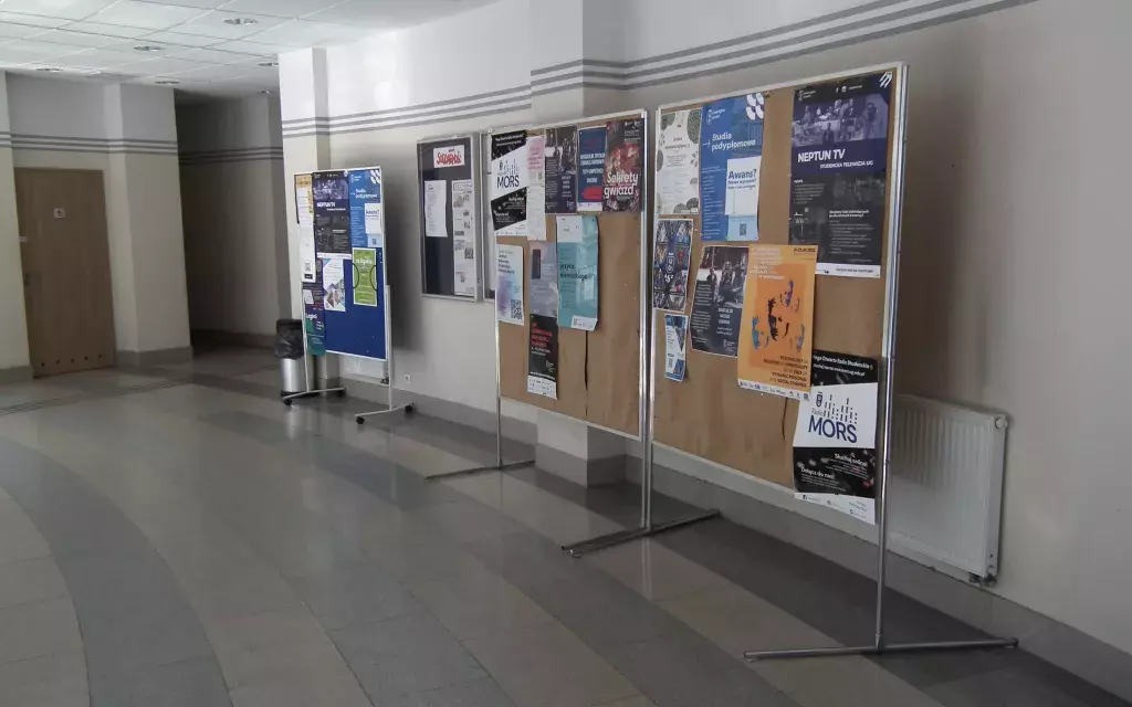 widok na tablicę reklamową z plakatami na parterze budynku Wydziału Nauk Społecznych