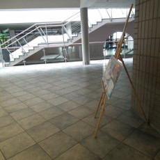 widok na fragment holu na 1 piętrze budynku Wydziału Prawa i administracji. Po prawej widać stand reklamowy na plakaty